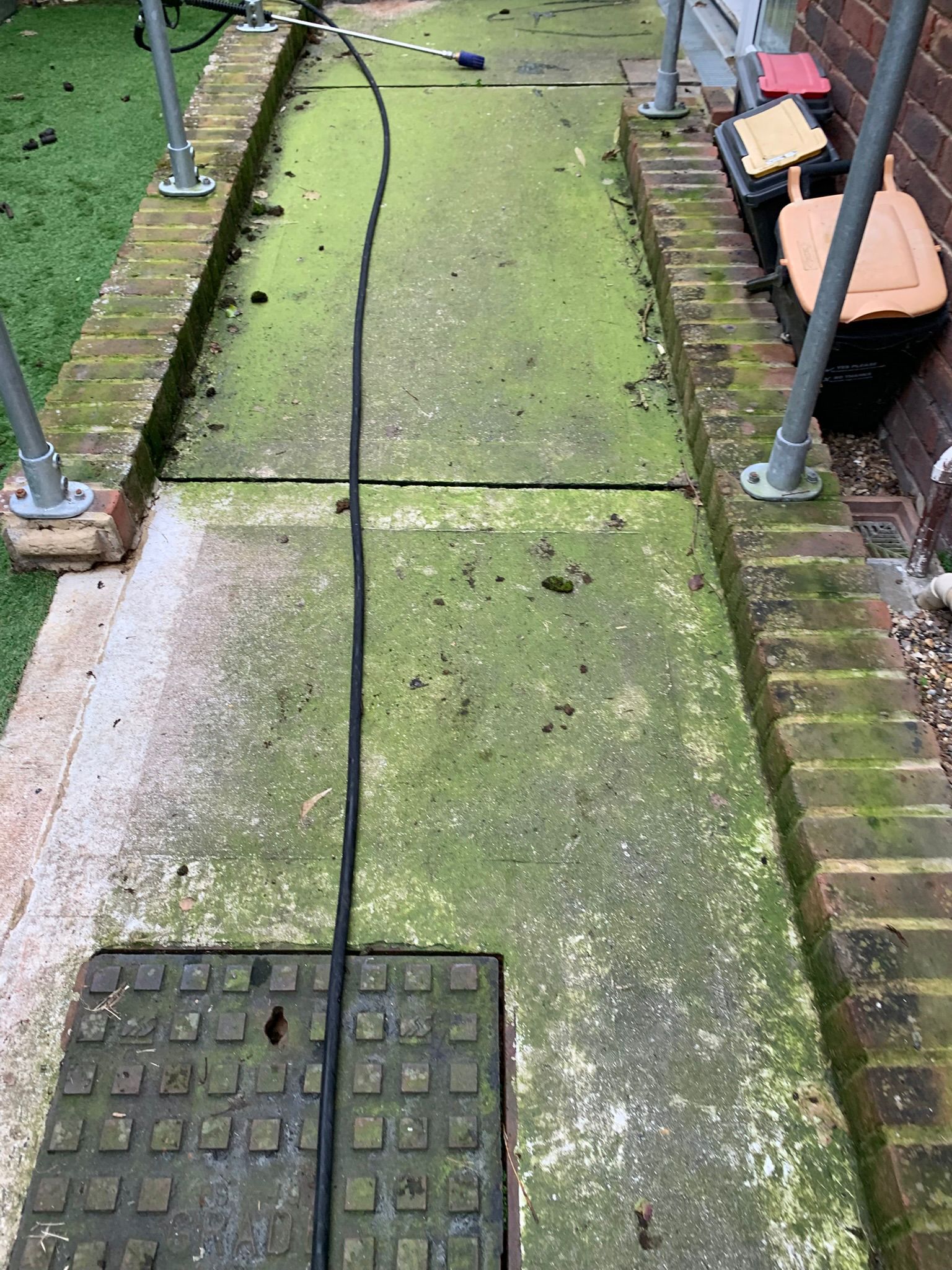 Concrete access path and ramp covered in green algae before pressure washing